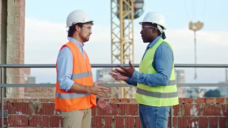 Multiethnic-two-men-in-hardhats-at-the-constructing-site.-African-American-and-Caucasian-builder-and-architect-talking,-solving-some-problems-and-shaking-hands.